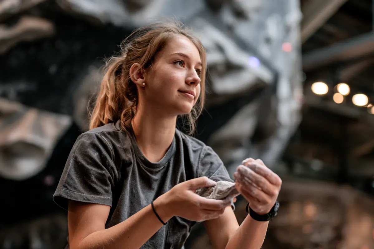 Young climber chalking up beside the bouldering wall